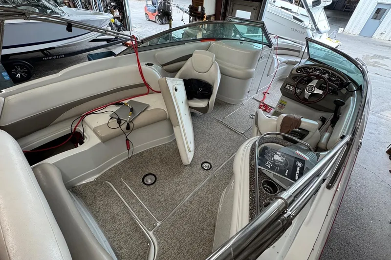 Slide: The Image of 2011 Crownline 252 EX boat interior with seating, steering wheel, and dashboard in a showroom. - 4