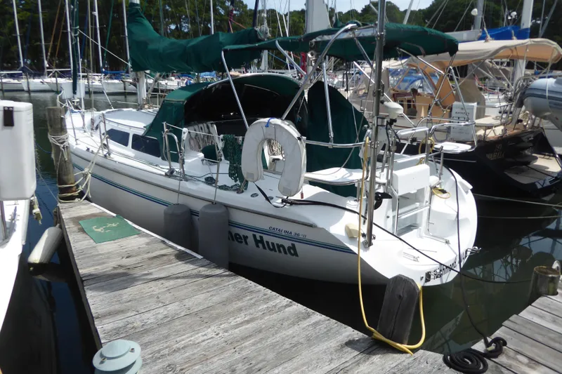 The Image of 1998 Catalina 36 MkII sailboat docked at a marina, featuring green canvas covers. - 0
