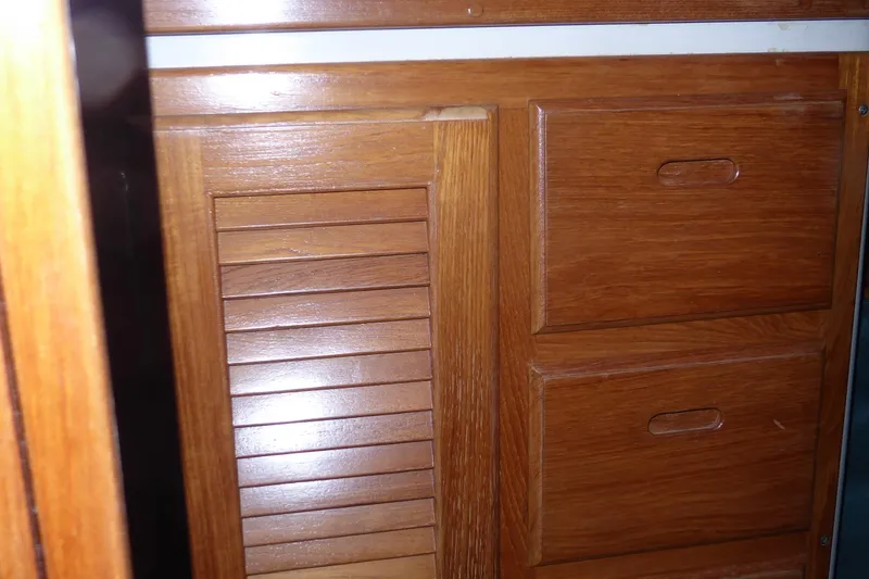 Slide: The Image of Wooden cabinetry inside a 1998 Catalina 36 MkII sailboat, featuring drawers and a louvered door. - 29