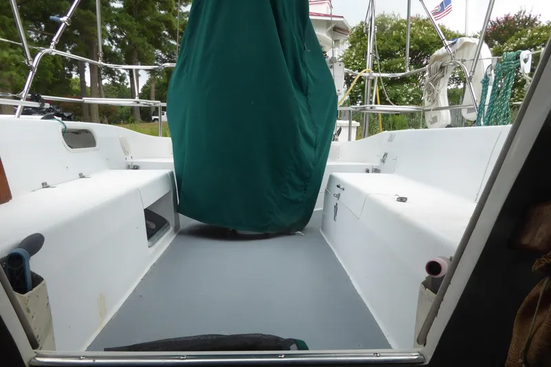 Slide: The Image of 1998 Catalina 36 MkII sailboat cockpit with green cover, surrounded by trees and American flag. - 32