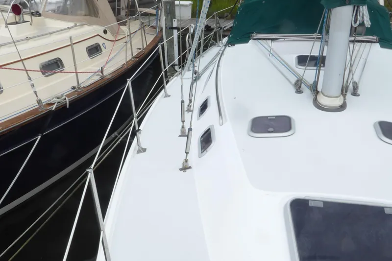 Slide: The Image of 1998 Catalina 36 MkII sailboat deck with rigging and hatches, docked beside another boat. - 44