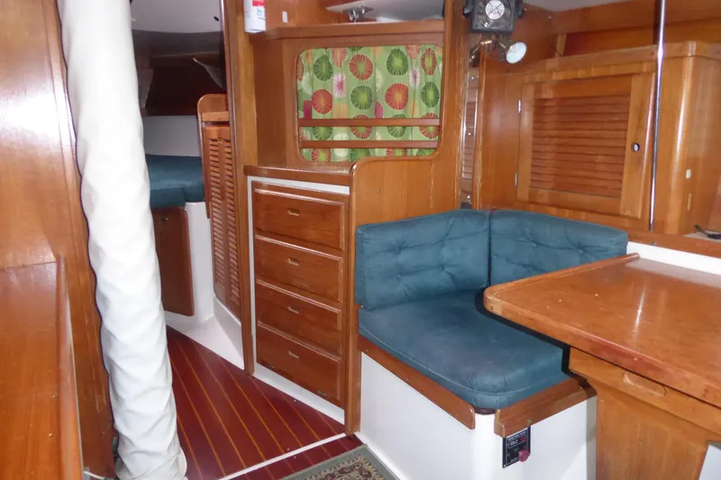 Slide: The Image of 1998 Catalina 36 MkII interior with wooden cabinetry, blue cushioned seating, and vibrant curtains. - 6