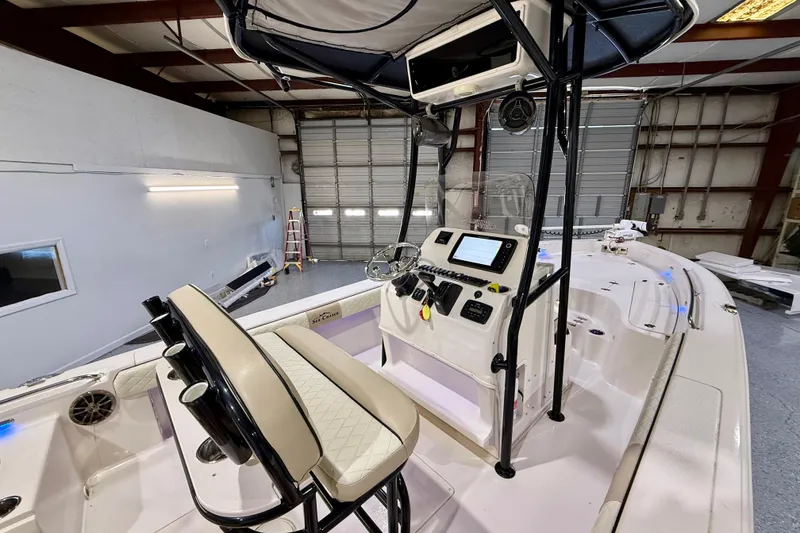 Slide: The Image of 2020 Sea Chaser 23 LX boat interior with helm, seating, and navigation equipment in a garage. - 22