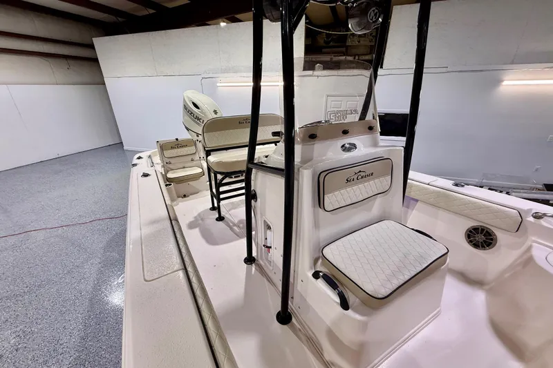 Slide: The Image of 2020 Sea Chaser 23 LX boat interior with seating and console in a showroom. - 27
