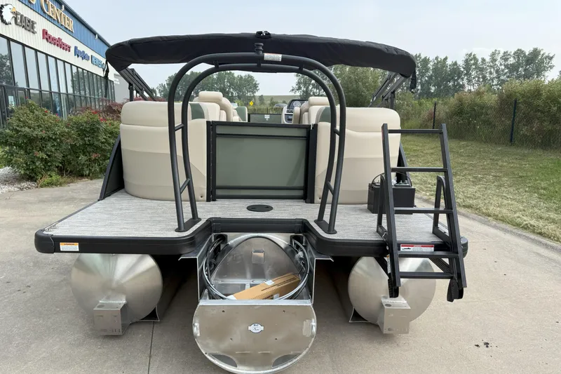 Slide: The Image of 2026 Godfrey SW 2286 SB pontoon boat with rear ladder and seating, parked outdoors. - 3
