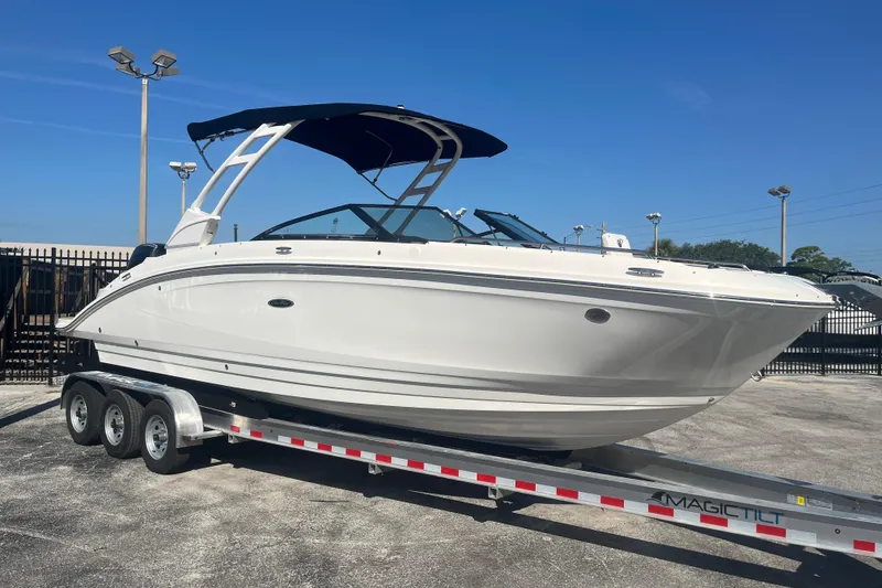 Slide: The Image of 2024 Sea Ray SDX 270 Outboard boat on trailer, displayed outdoors under clear blue sky. - 2