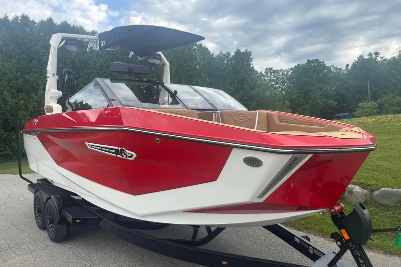 Slide: The Image of 2025 Nautique G23 boat in vibrant red and white, parked on a trailer. - 10