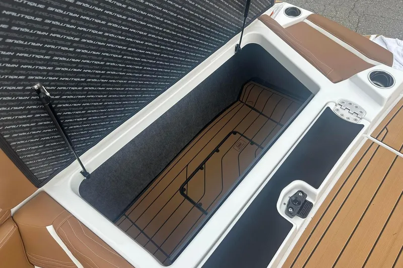 Slide: The Image of 2025 Nautique G23 boat storage compartment with brown seating and cup holders. - 16
