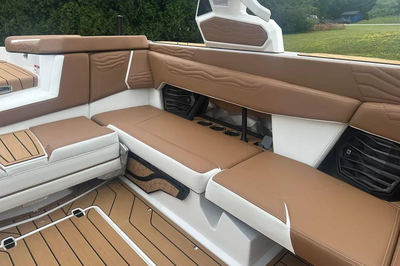 Slide: The Image of 2025 Nautique G23 boat interior with tan and white seating, cup holders, and speakers. - 19