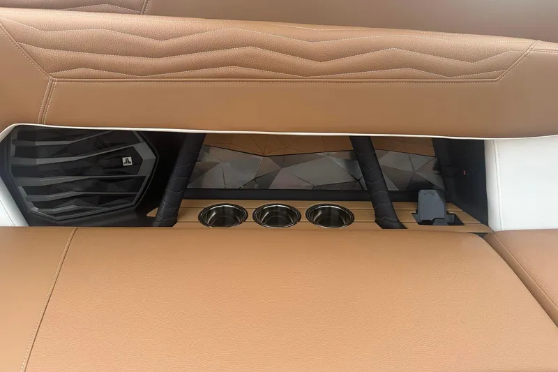 Slide: The Image of 2025 Nautique G23 interior with tan leather seats, speaker, and cup holders. - 22