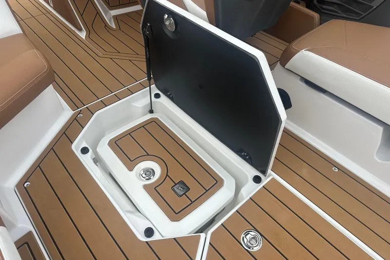Slide: The Image of 2025 Nautique G23 boat interior with open storage compartment and teak-style flooring. - 23