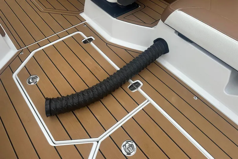 Slide: The Image of 2025 Nautique G23 boat deck with brown flooring and black hose detail. - 24