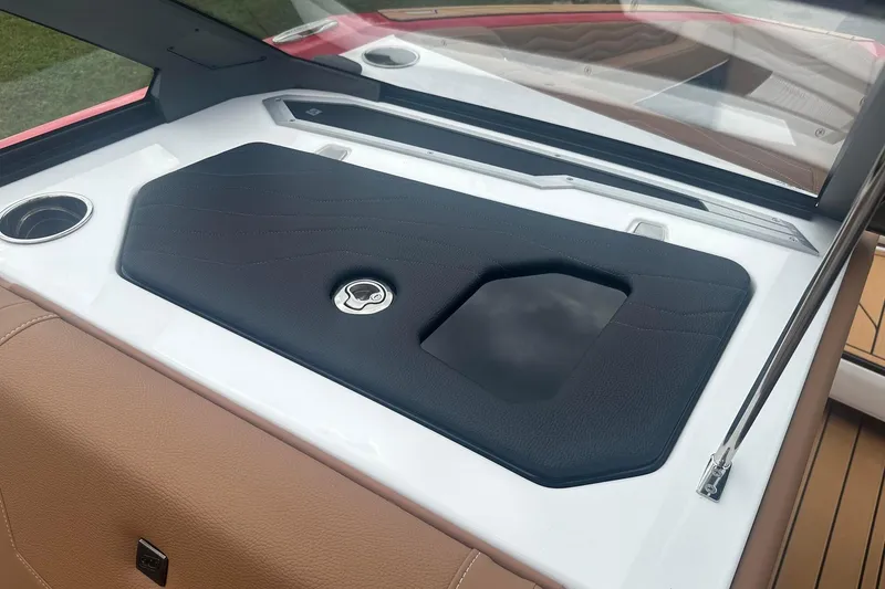 Slide: The Image of 2025 Nautique G23 boat interior with sleek black and tan design, featuring cup holders. - 26