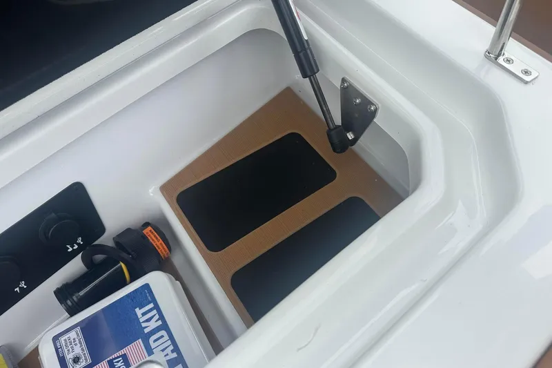 Slide: The Image of 2025 Nautique G23 storage compartment with safety kit and accessories. - 27