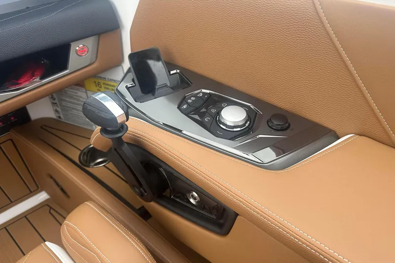 Slide: The Image of 2025 Nautique G23 boat interior with tan leather, control panel, and phone holder. - 29