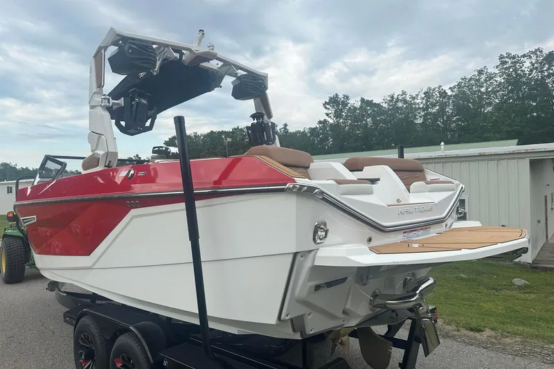 Slide: The Image of 2025 Nautique G23 boat with red and white design on a trailer, parked outdoors. - 3