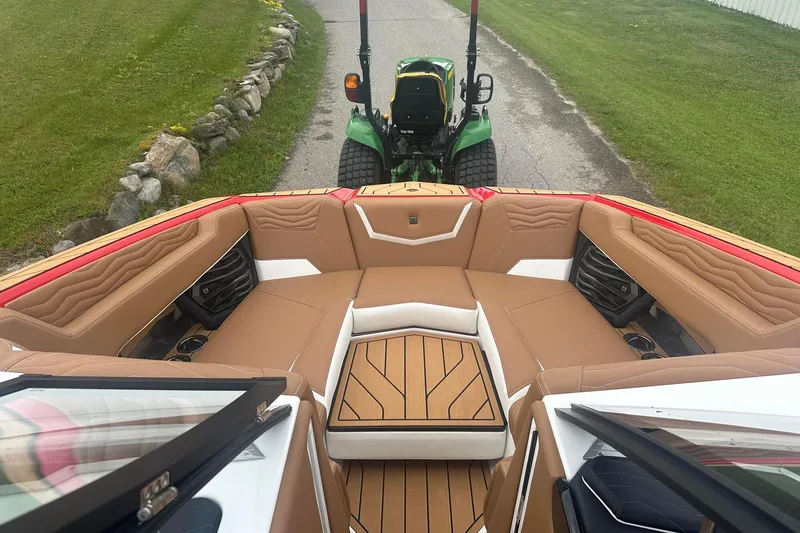 Slide: The Image of 2025 Nautique G23 boat interior with tan seating, viewed from above, near a green tractor. - 33