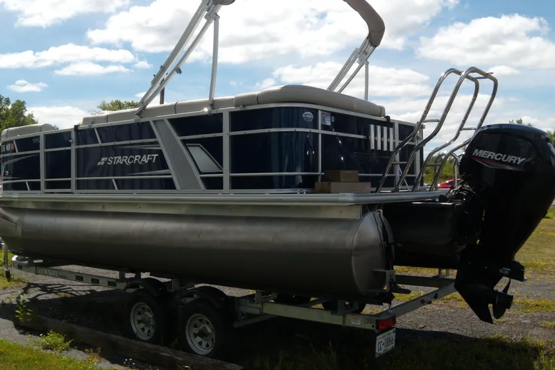 Slide: The Image of 2020 Starcraft EX 20 C pontoon boat on trailer with Mercury outboard motor. - 2