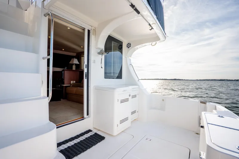 Slide: The Image of 2005 Silverton 34 Convertible yacht deck with open cabin door, overlooking serene waters. - 15