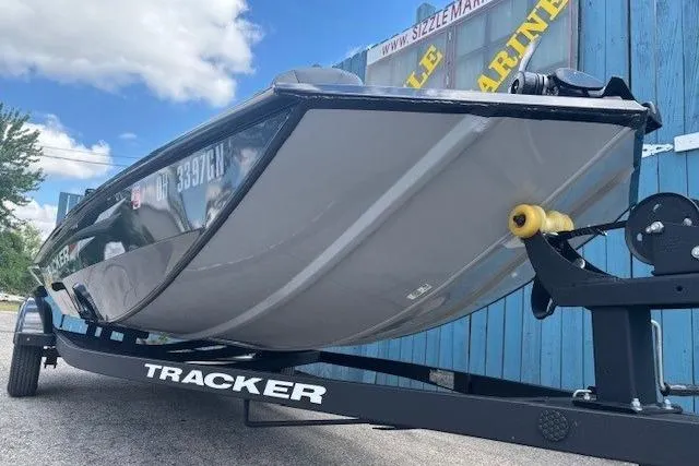Slide: The Image of 2025 Tracker Pro 170 boat on trailer, parked outdoors near blue building. - 2