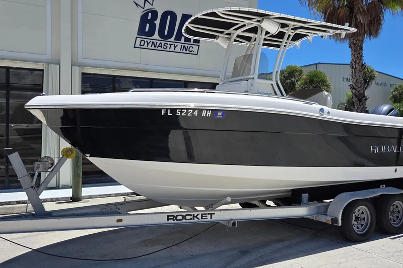Slide: The Image of 2017 Robalo R222 Center Console boat on trailer, parked outside a building. - 2