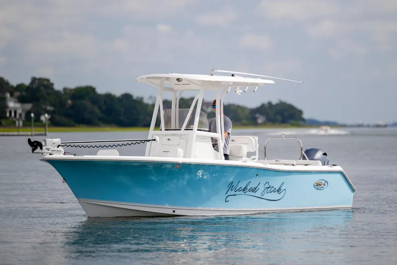 The Image of 2016 Sea Hunt Ultra 225 boat on calm water, featuring a sleek blue design. - 0