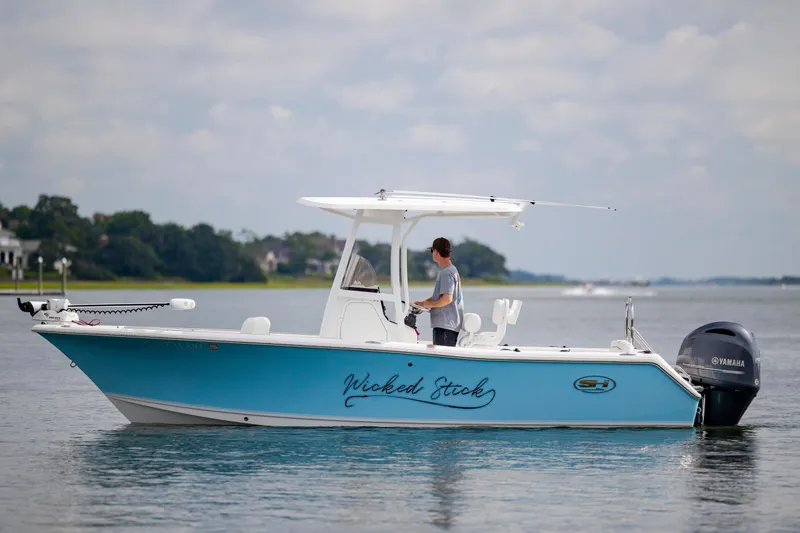 Slide: The Image of 2016 Sea Hunt Ultra 225 boat on calm water, person standing at helm. - 1