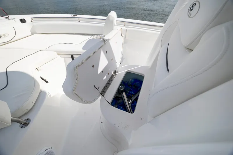 Slide: The Image of 2016 Sea Hunt Ultra 225 boat interior with open storage compartment and white seating. - 13