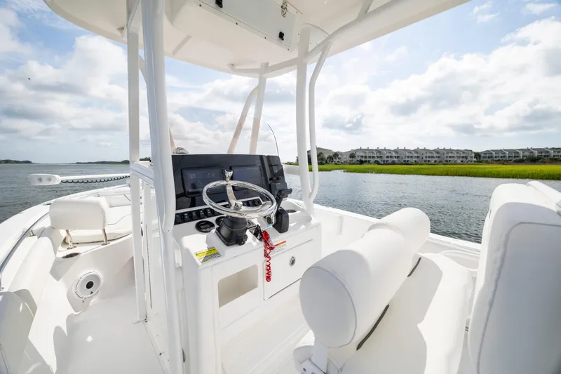 Slide: The Image of 2016 Sea Hunt Ultra 225 boat interior with steering wheel, on a sunny day by the water. - 15