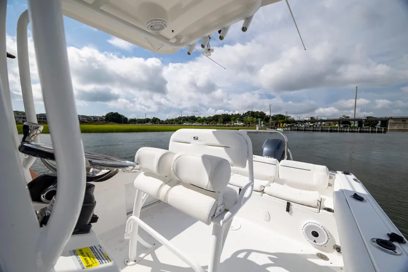 Slide: The Image of 2016 Sea Hunt Ultra 225 boat interior with white seating, steering wheel, and water view. - 16