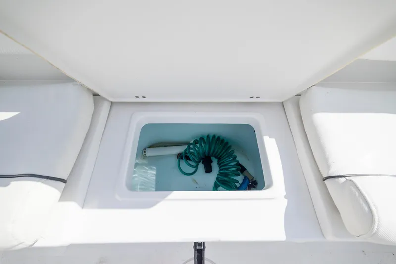 Slide: The Image of Storage compartment on 2016 Sea Hunt Ultra 225 boat with coiled hose inside. - 20