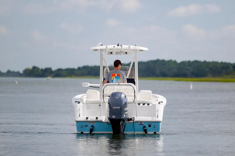 Slide: The Image of 2016 Sea Hunt Ultra 225 boat cruising on a calm lake with scenic background. - 3