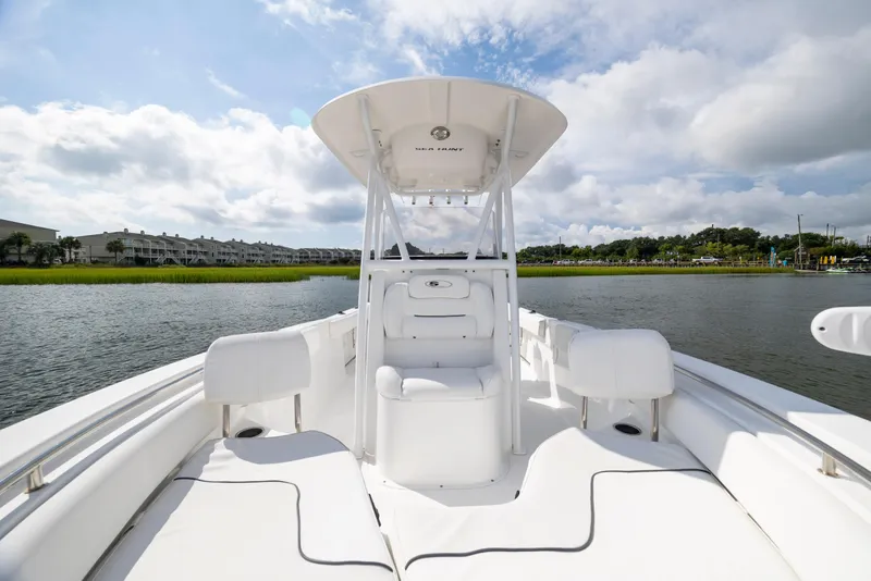 Slide: The Image of 2016 Sea Hunt Ultra 225 boat interior with white seating, on a calm waterway. - 9