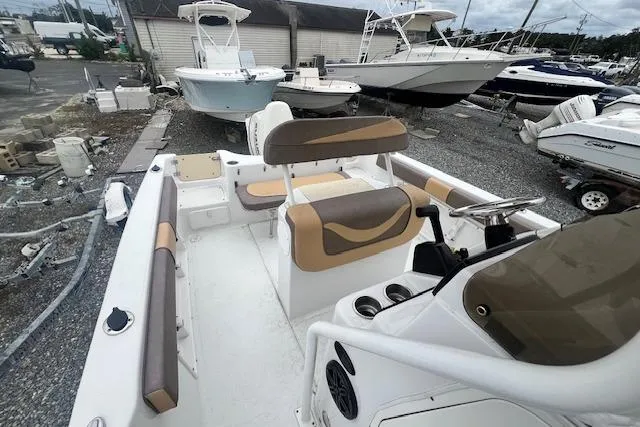 Slide: The Image of 2019 Key Largo 2100 WI boat interior with seating and steering console in a marina setting. - 5