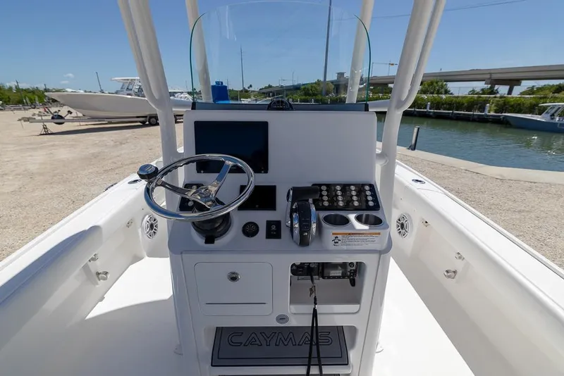 Slide: The Image of 2022 Caymas 26 HB boat console with steering wheel and controls, docked near water. - 12