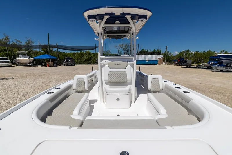 Slide: The Image of 2022 Caymas 26 HB boat interior with seating and console, parked outdoors under clear sky. - 16