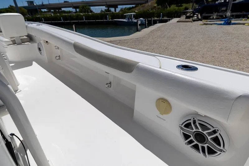 Slide: The Image of 2022 Caymas 26 HB boat interior with speakers and seating, docked by the water. - 18
