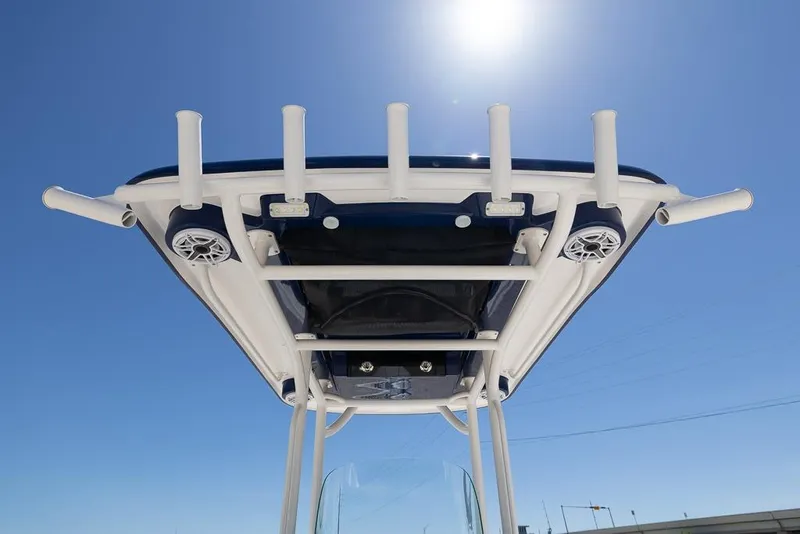 Slide: The Image of 2022 Caymas 26 HB boat T-top with rod holders and speakers under clear blue sky. - 20