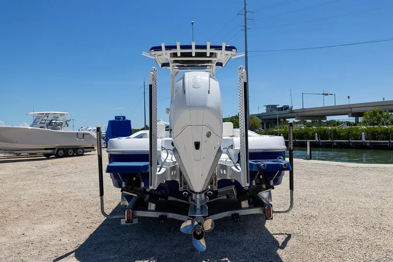 Slide: The Image of 2022 Caymas 26 HB boat with powerful outboard motor, parked on gravel near water. - 4