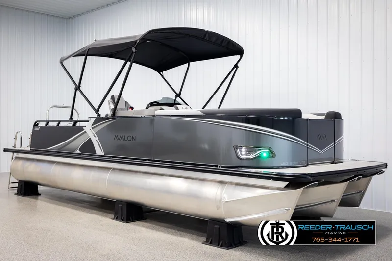 Slide: The Image of 2026 Avalon LSZ VRB pontoon boat with canopy in showroom, Reeder-Trausch Marine branding. - 3