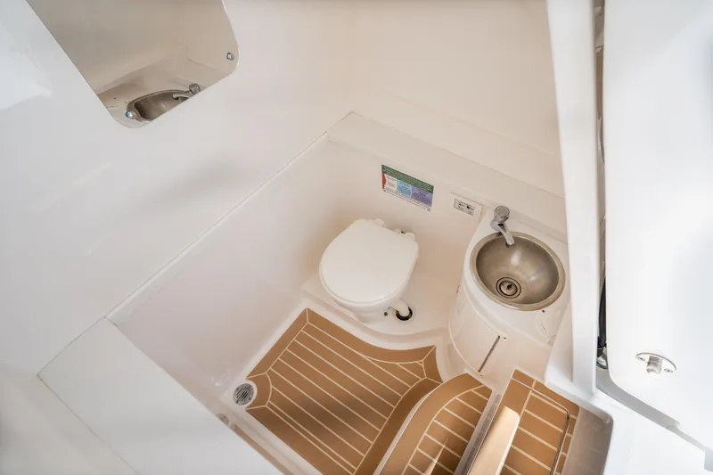 Slide: The Image of 2018 Intrepid 375 Open boat bathroom with toilet, sink, and wooden floor mat. - 29