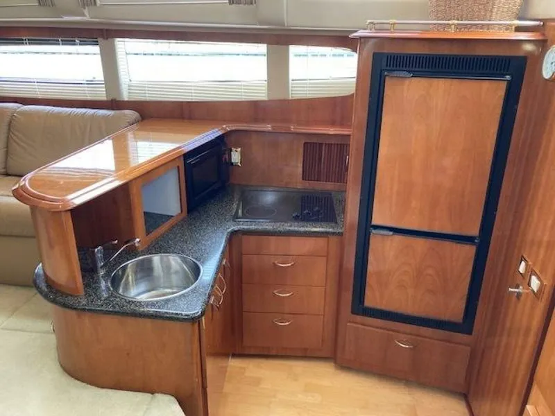 Slide: The Image of 2003 Carver 396 Aft Cabin MY yacht interior with kitchenette, featuring wood cabinetry and modern appliances. - 8