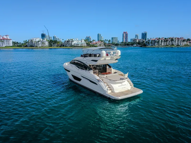 Slide: The Image of 2018 Princess S60 yacht cruising in clear blue waters near a city skyline. - 2