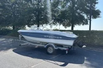 Slide: The Image of 2011 Bayliner 185 Bowrider boat on trailer, parked outdoors near trees. - 7