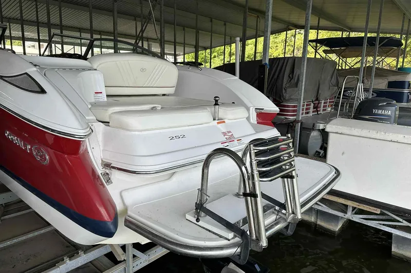 Slide: The Image of 2008 Cobalt 252 boat docked, featuring red and white design with swim platform and ladder. - 25