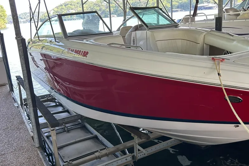 Slide: The Image of 2008 Cobalt 252 boat with red hull, docked on a lift by a lake. - 6