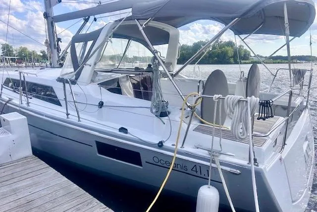 Slide: The Image of 2017 Beneteau Oceanis 41.1 sailboat docked by a serene waterfront. - 2
