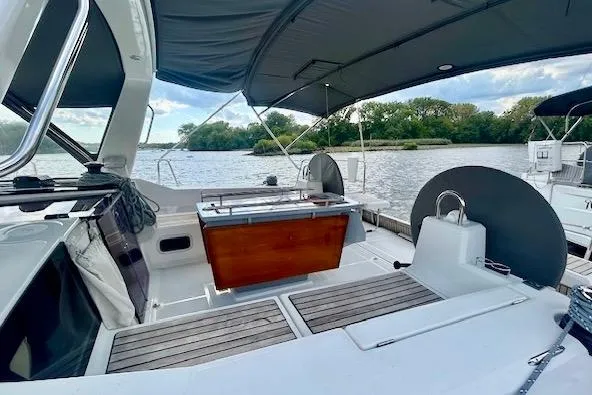 Slide: The Image of 2017 Beneteau Oceanis 41.1 sailboat cockpit with canopy, docked by a scenic river. - 6