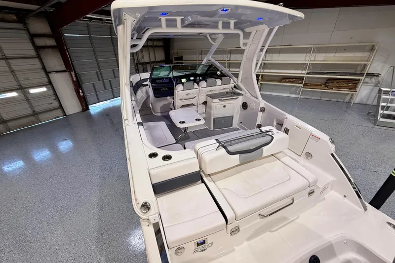 Slide: The Image of 2021 Chaparral 280 OSX boat interior with seating and helm in a garage setting. - 18