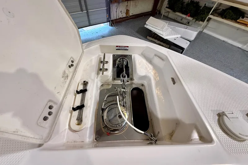 Slide: The Image of 2021 Chaparral 280 OSX boat anchor compartment with open hatch in a garage setting. - 39